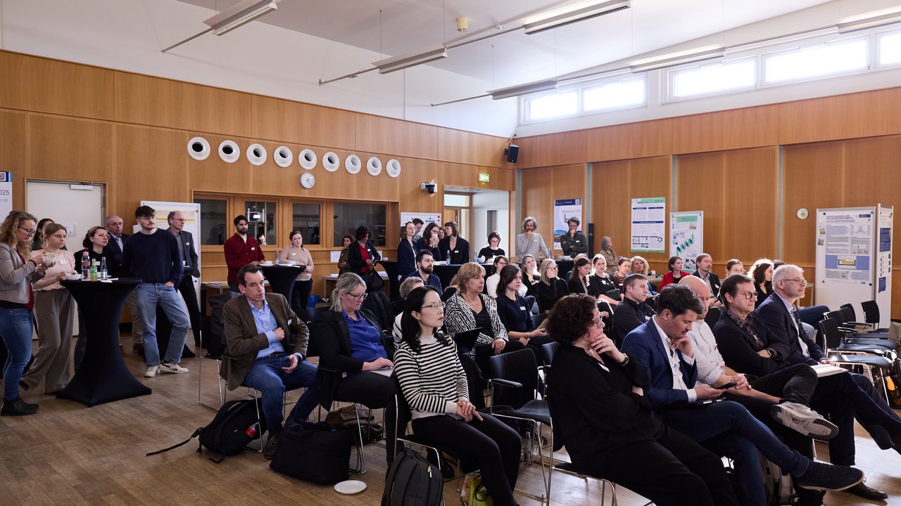 Personen sitzen in Reihen in einem Saal.